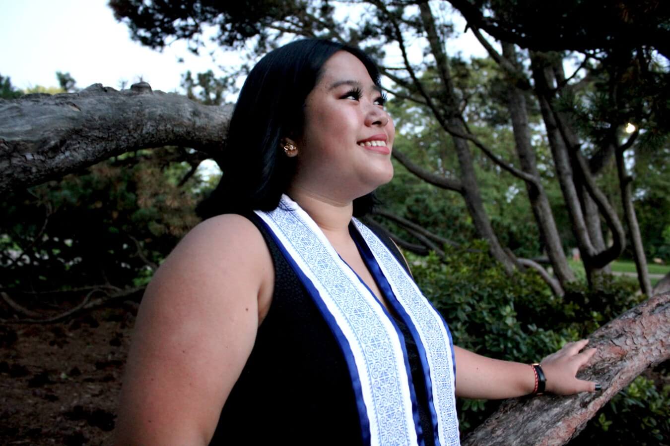 Digital color photograph of a women standing next to a tree.