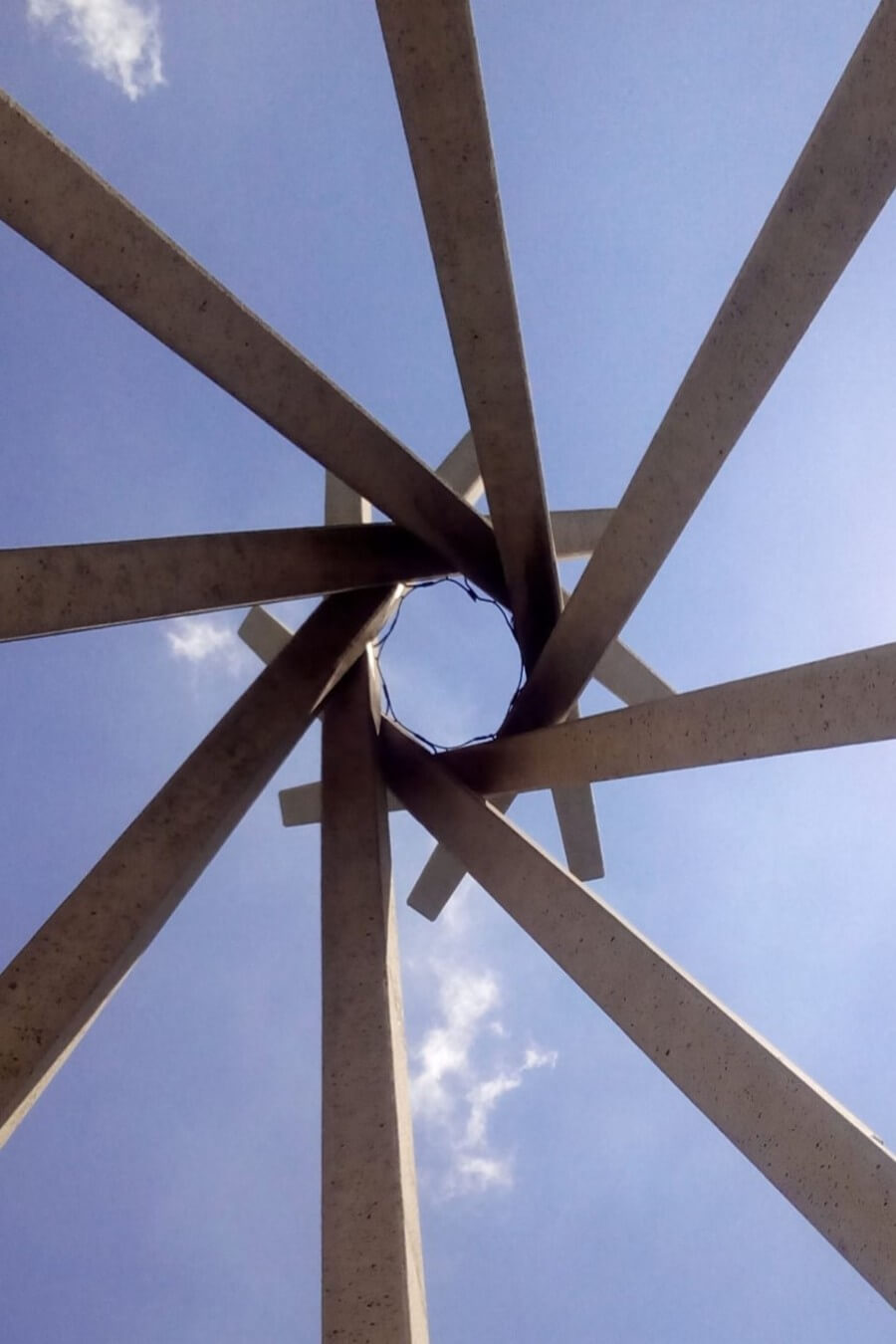 Metal concrete sculpture against a mostly sunny sky.